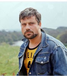 A photos of Oliver Reed in a denim jacket and yellow ring T-shirt. 