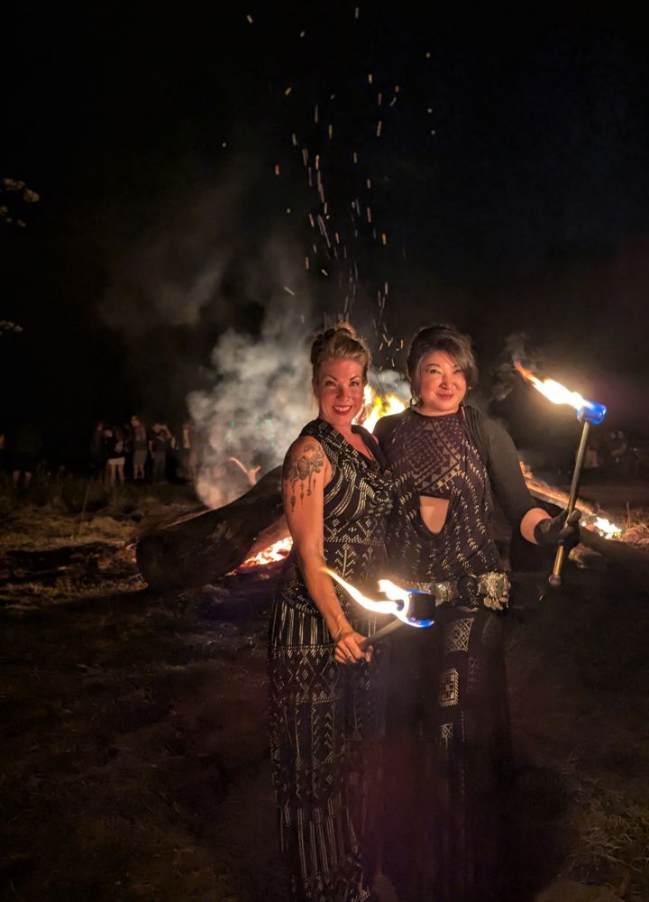 Firespinners posing by a massive bonfire. 
