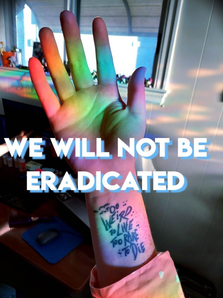 Photo is of a pale hand that's catching a beam of rainbow. On the wrist is a tattoo that says "too weird to live too rare to die" and over the image itself is the text "WE WILL NOT BE ERADICATED."