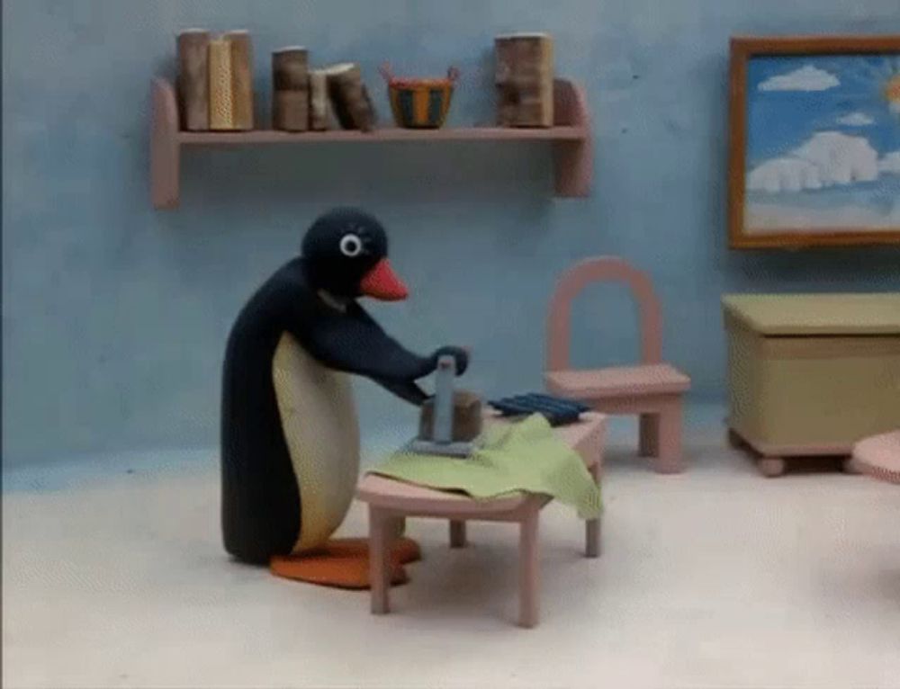 a penguin is ironing a piece of cloth on a table in a room