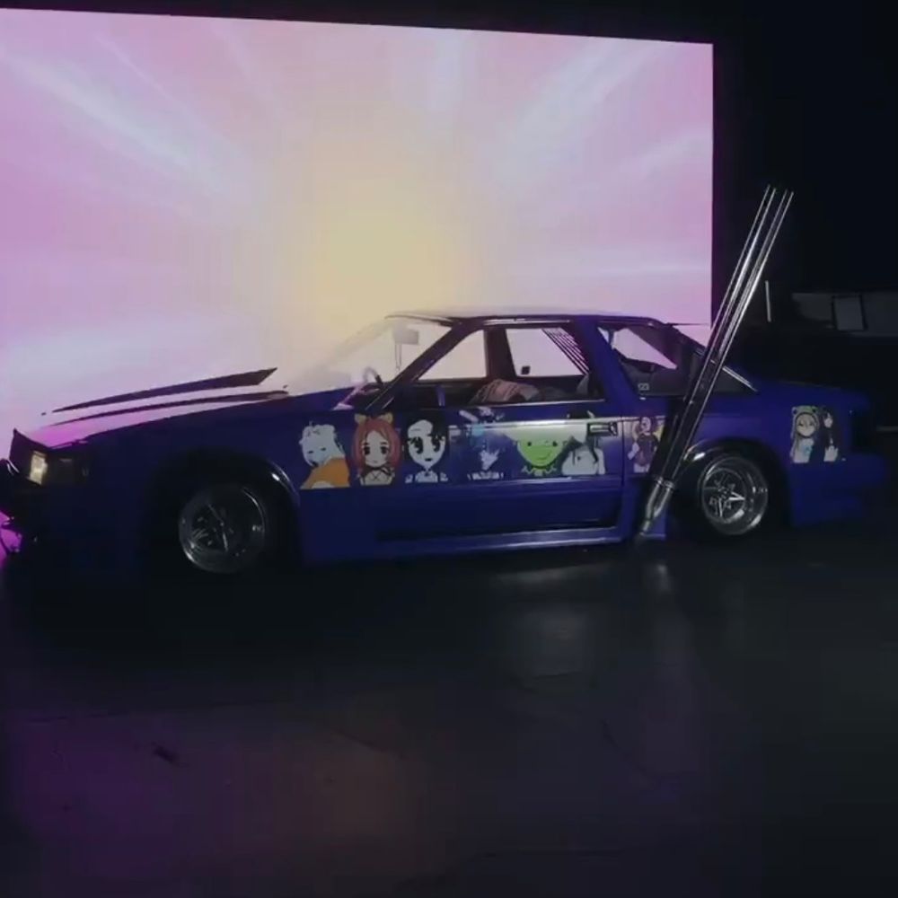 Wide shot of a purple car with many vtuber cutouts on it, including an image from my stream!