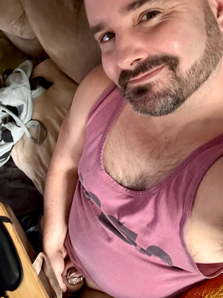 Selfie of me holding my balls.  I’m wearing a dark pink tank top, and my nub in its metal cage is clearly visible.