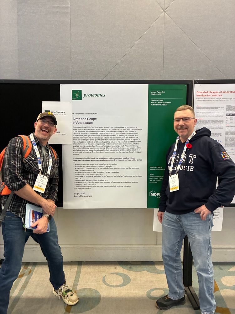 Editorial Board Member Dr. Benjamin Orsburn (left) and Editor-in-Chief Prof. Dr. Jens R. Coorssen (right) in front of the Proteomes poster at HUPO 2025.