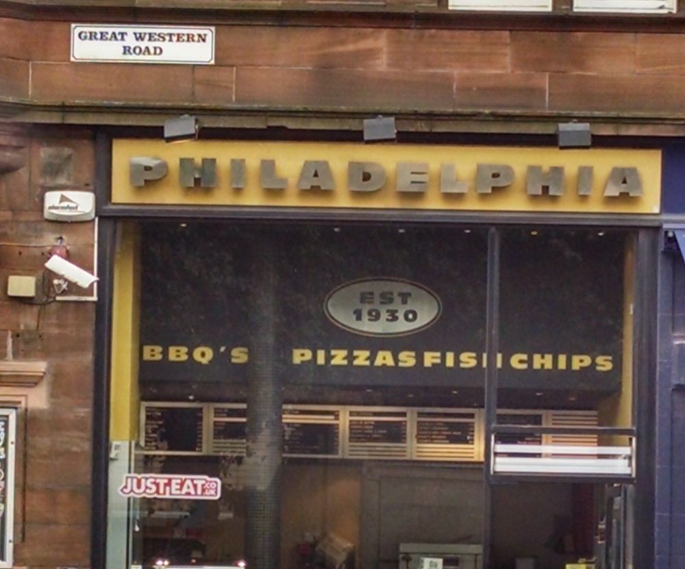 A store with a sign reading

Philadelphia
Est 1930
BBQ's Pizzas Fish Chips