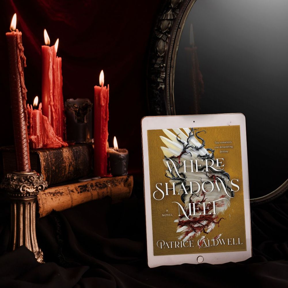 Where Shadows Meet by Patrice Caldwell is shown on a tablet. In the background are melted red candles, old books, a mirror, and draped fabric. 