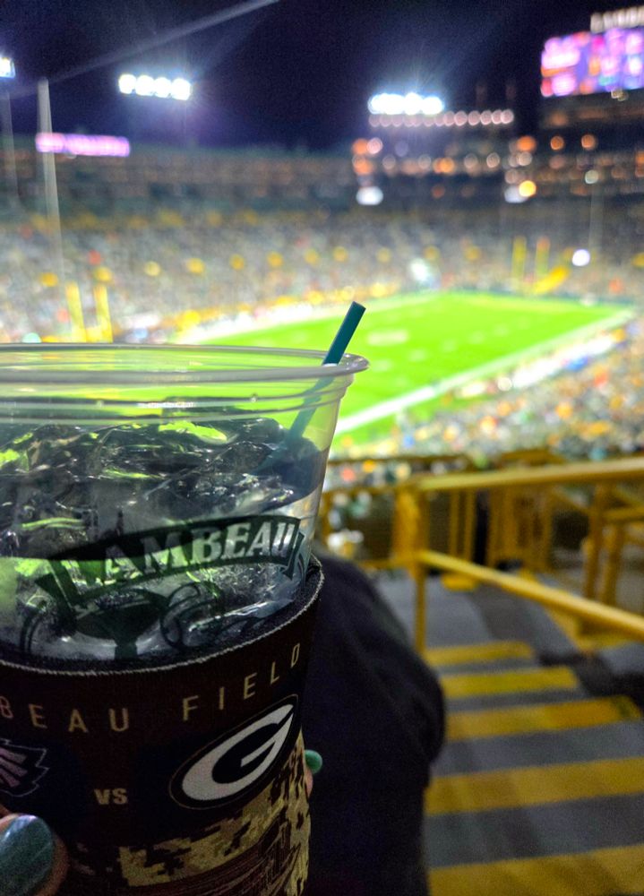 vodka soda in a coozie with lambeau field in the background 