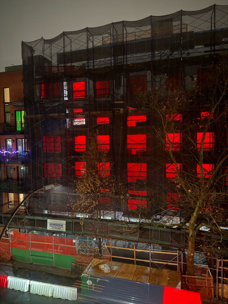 Apartment building under construction with red tarps, covering the windows
