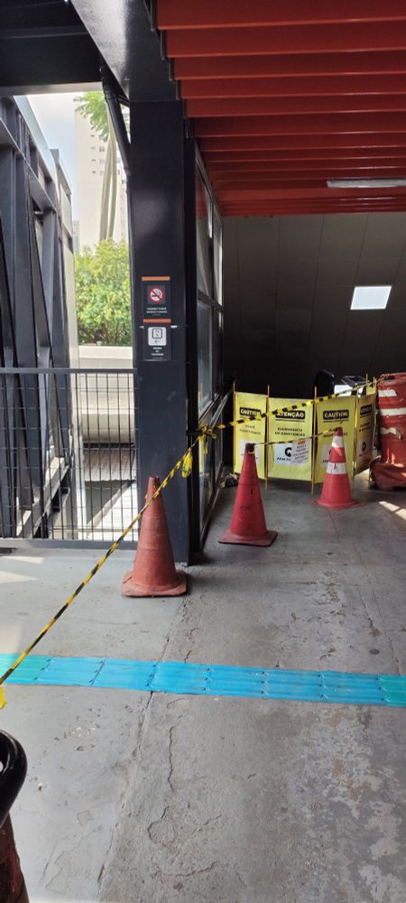 Foto colorida ampliada da escada rolante parada na parte direita da foto, e do lado esquerdo uma fita impedindo a entrada para o elevador, que também está parado.