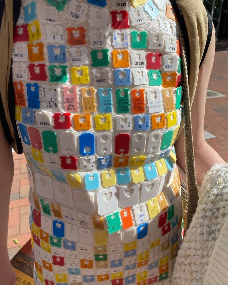 Pic of a person wearing a dress that is coated with an assortment (color, shape) of bread clips 
