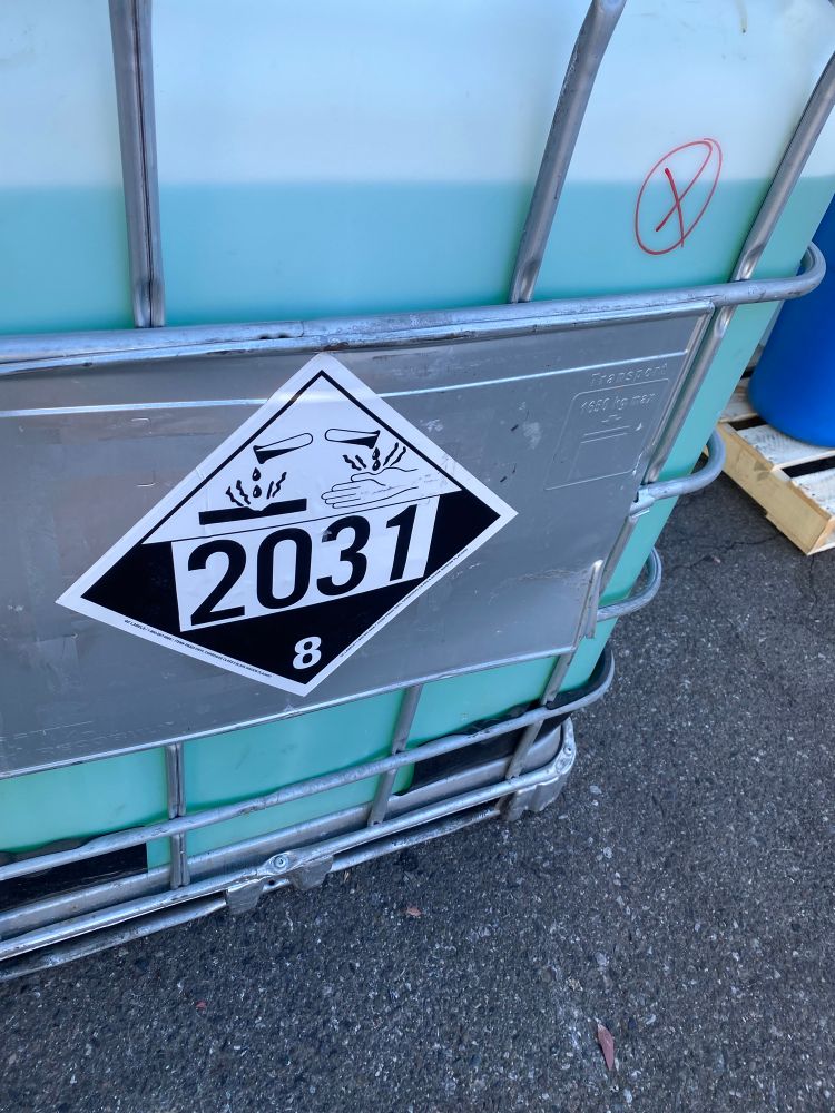 Front view of a tote of nitric acid w/ 2031 corrosive placard