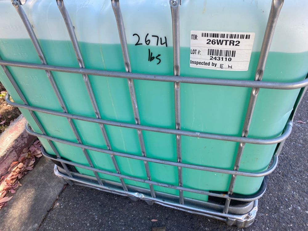 Side view of a tote of nitric acid, teal-ish color