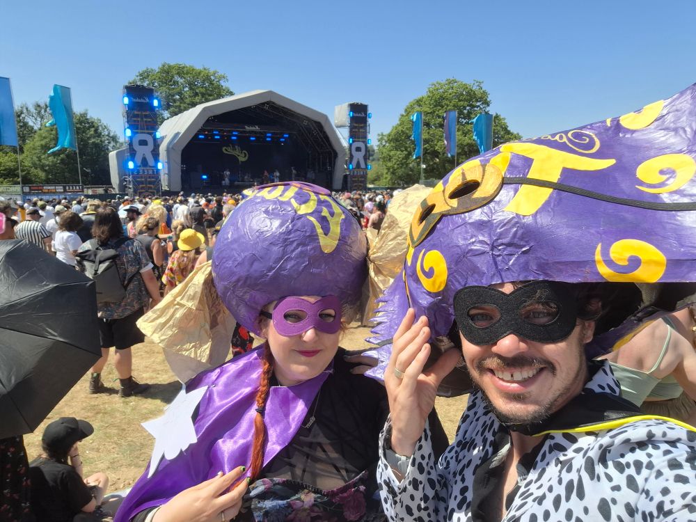 Photo of us in front of a stage with the heads balanced above our faces and masks on