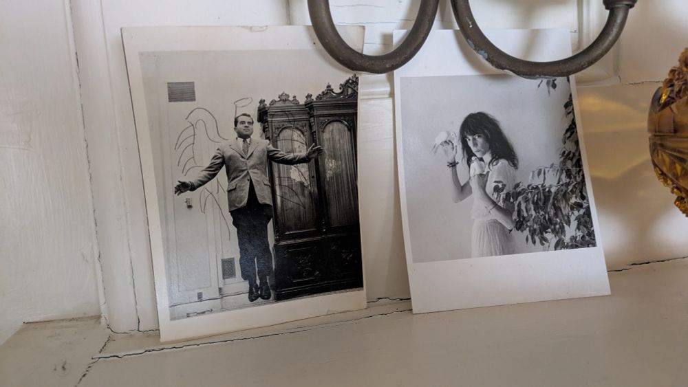 closeup two black and white photograph postcards on a white mantel
first is Richard Nixon jumping 1956 by Philippe Halsmann - smiling Nixon in sportscoat and tie jumps straight up a few inches with his arms outstretched - I penciled in some wings
second is Patti Smith 1979 by Robert Mapplethorpe - she's posed wearing white linen dress with a white dove perched on each hand as she stares moodily