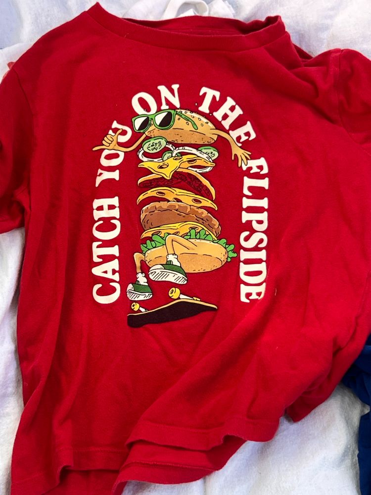 If this hadda fit, I woulda bought it. Red t-shirt showing a hamburger with all the trimmings doing skateboard tricks. Says “Catch you on the flip side.” Sized for a 12 year old.