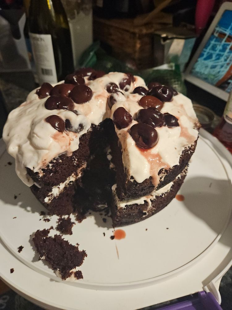A vegan black forest cake with a slice taken out.