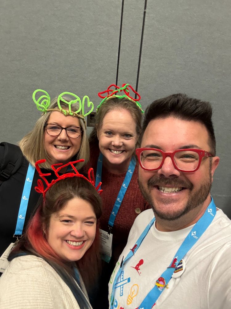 Jed Dearybury and three women wearing pipecleaner "hats" one that says FETC, one that had hearts on it, and one with a heart, peace sign, and swirl. 
