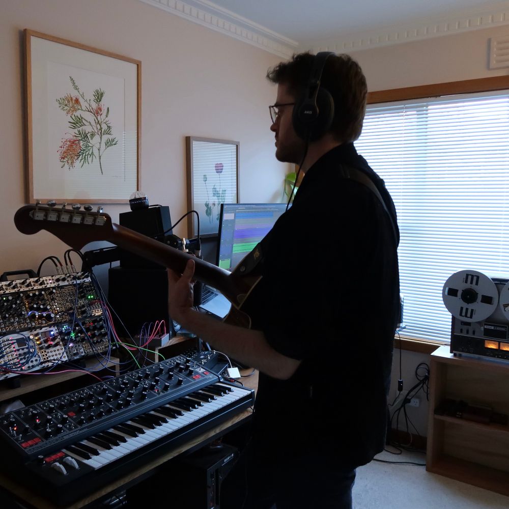 Photo of Spectrical playing acoustic guitar in a room with various music equipment