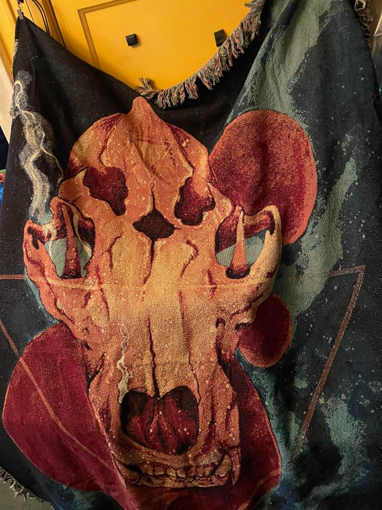 Large blanket featuring a fantasy animal skull; image is slightly distorted from fabric draping 