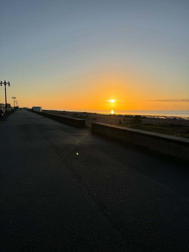 Sunrise over a dark sea and pebbly beach 