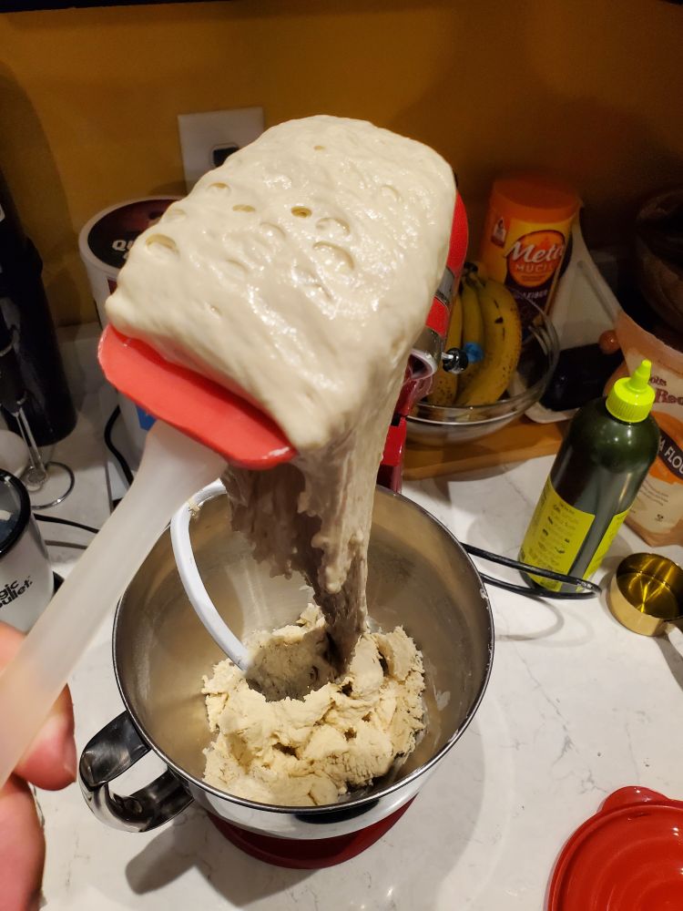 Poolish spooled off of a plastic mixing spatula into a mixer bowl. 