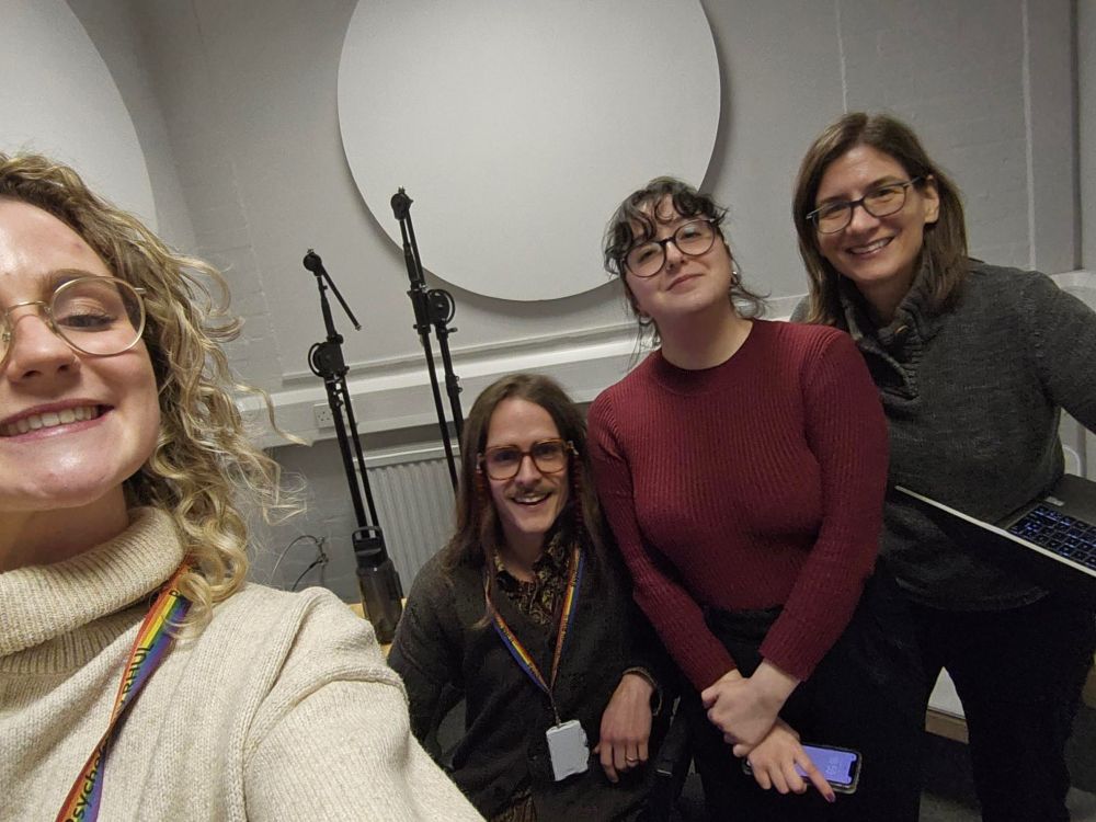 Gemma, Ryan, Gaia and Teale are all smiling in a podcast studio with recording mics behind them. 