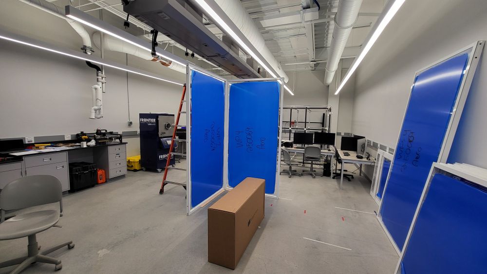 Two tall blue panels standing upright form the start of a wall inside a contemporary lab space.