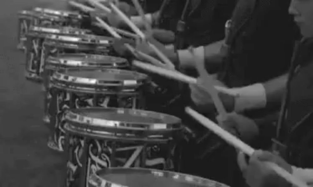 a black and white photo of a marching band playing drums