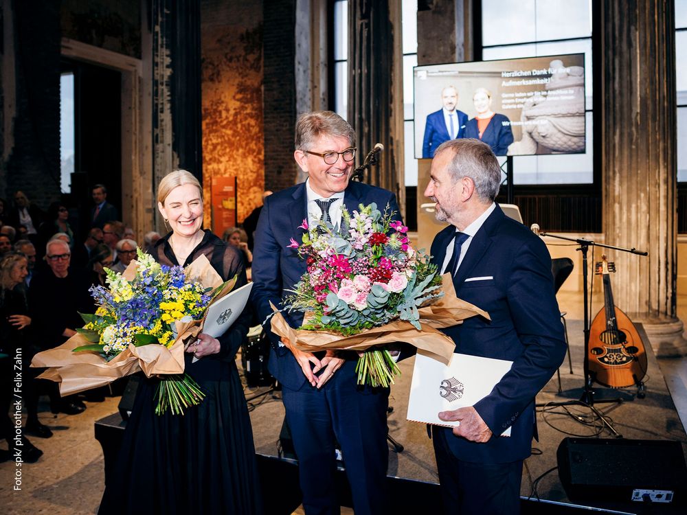 Wolfram Weimer übergibt Blumensträuße an Marion Ackermann und Hermann Parzinger.
