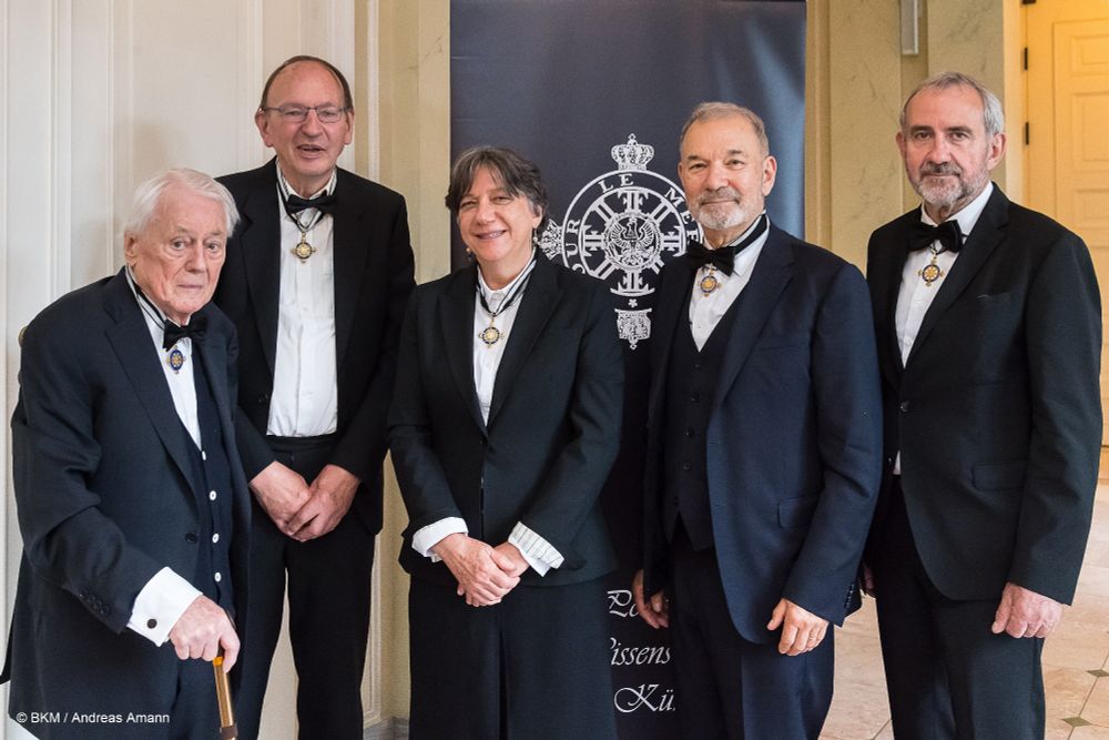Die neuen Ordensmitglieder posieren mit ihren Orden zusammen mit Ordenspräsidenten Hermann Parzinger vor dem Emblem des Ordens pour le mérite. 