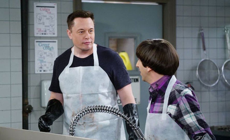 Elon Musk, wearing a white apron and gloves, on the Big Bang Theory playing a version of himself who would volunteer at a soup kitchen. He is talking to the pervert character Howard.