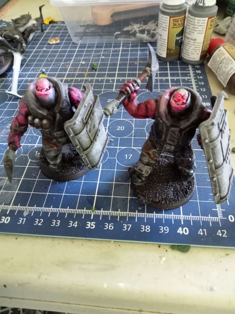 two large skull-headed brutes with bullet-proof shields, one with an axe, one with a pick-axe