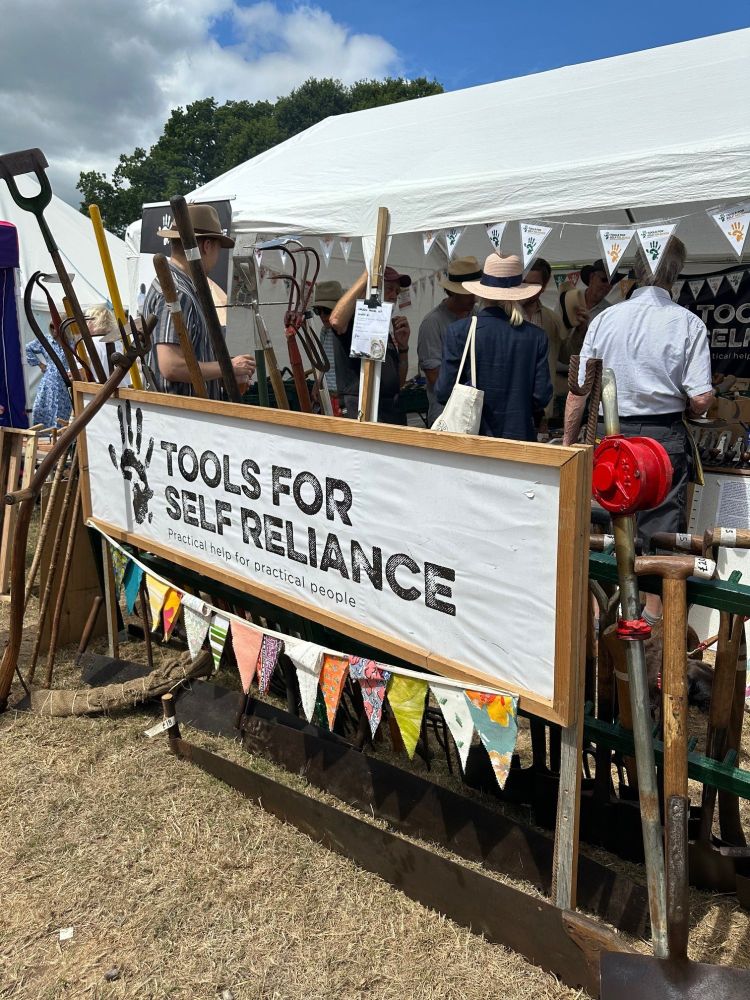 A big sign in front of our stand which says Tools for Self Reliance, some bunting hanging off it. People inside the stand looking for refurbished tools. Circular economy in action!
