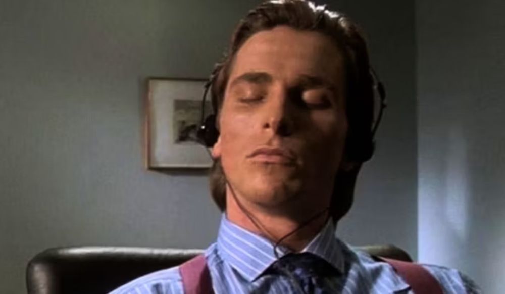 Patrick Bateman, played by Christian Bale from American Psycho, listens to music.