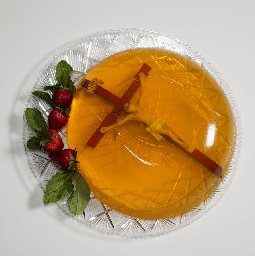 A Catholic crucifix embedded in molded yellow Jello, garnished with strawberries.