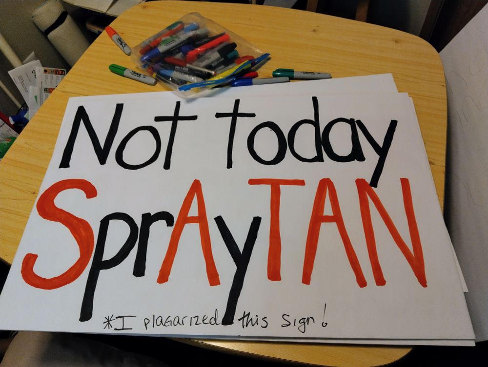 Small table during with markers. A poster board reads: not today SprAy TAN
Smaller text reads: *I plagiarized this sign*