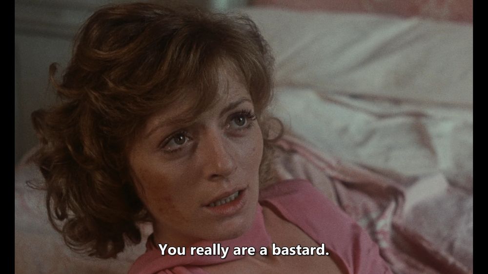 A screenshot from Spermula. A woman with blood smeared on her cheek looks up at a man, offscreen. The subtitle reads "You really are a bastard."
