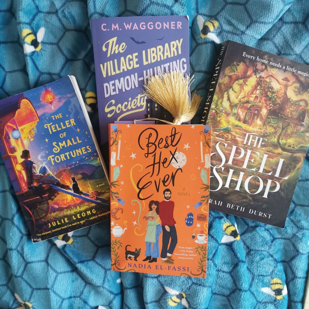 The Read and Current Read: 

Right - The Spell Shop by Sarah Beth Durst (the book that started my Cozy Girl Era at the end of March).

Left - The Teller of Small Fortunes by Julie Leong (the second book)

Middle Top - The Village Library Demon-Hunting Society by C. M. Waggoner (the most recent finished)

Middle Bottom - Best Hex Ever (current read, hella representative of EVERYTHING like this is GOLD TIER) 