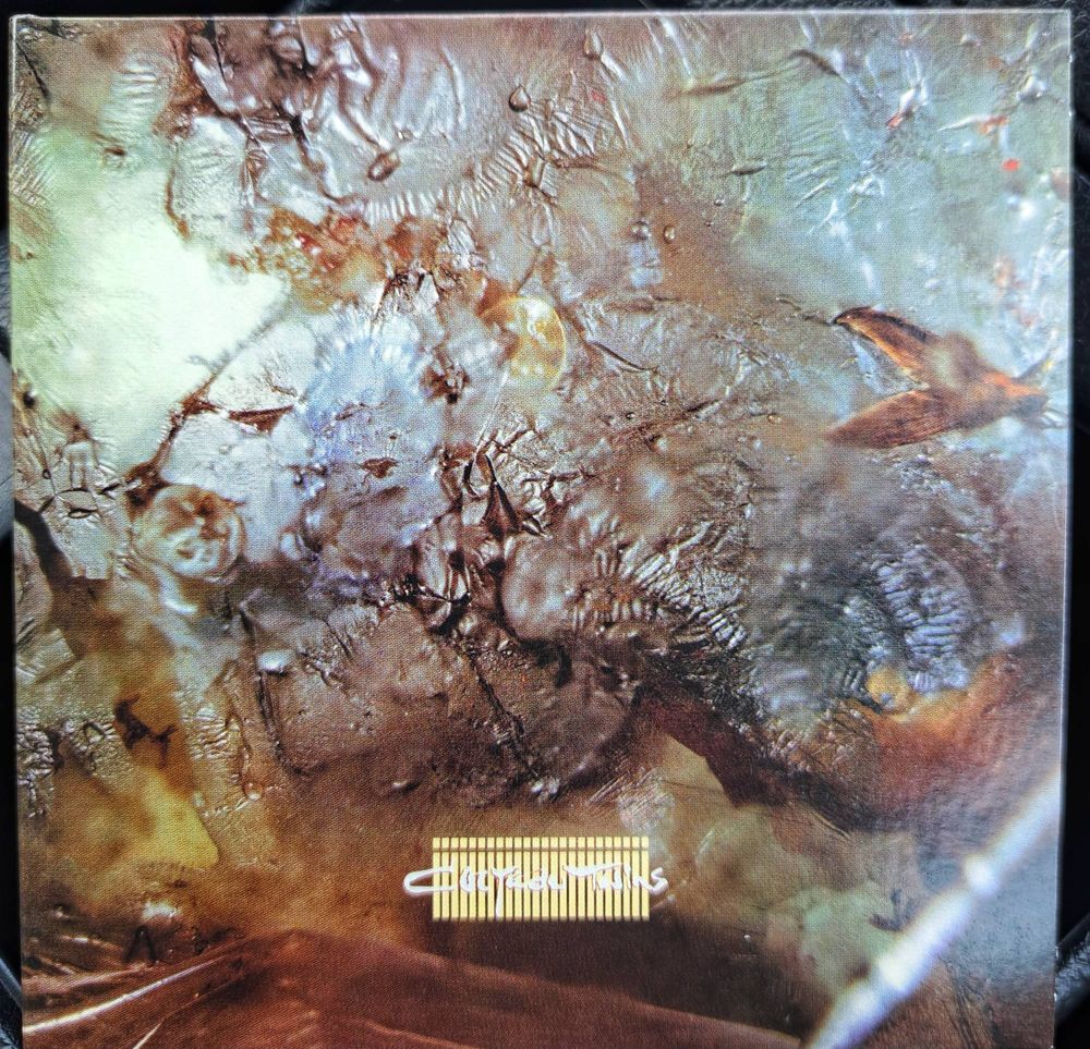 This is a picture of the CD version of the album Head Over Heels by the band Cocteau Twins. It’s sort of browny grey, and a bit like looking at pebbles underwater. Very arty, but then this is the 4AD label.