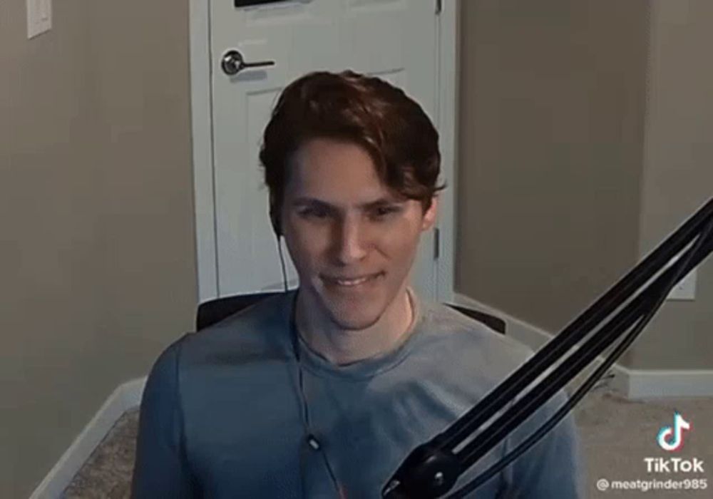 a young man is sitting in front of a microphone wearing headphones and smiling .