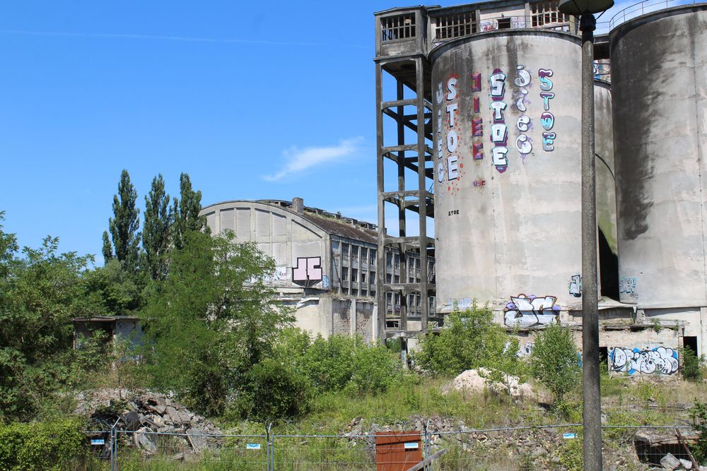 Altes Zementwerk, Rüdersdorf bei Berlin 2018
Zwei verfallende Solios und eine alte Halle zwischen Schuttbergen und Gestrüpp im Sonnenlicht.