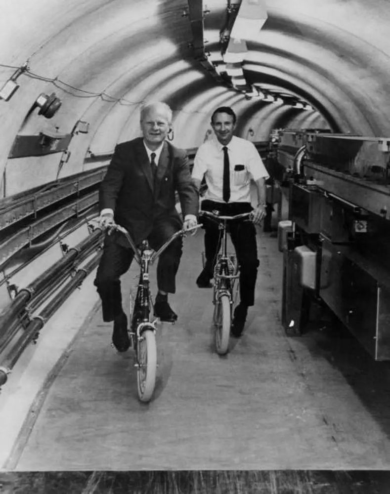 Hans Bethe and Boyce McDaniel riding bikes around the Wilson Synchrotron