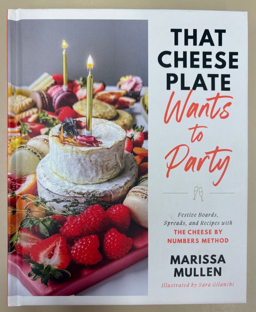 Book cover of That Cheese Plate Wants to Party by Marissa Mullen. It had a colorful platter covered with red berries, cheese rounds with candles, crackers & cookies.