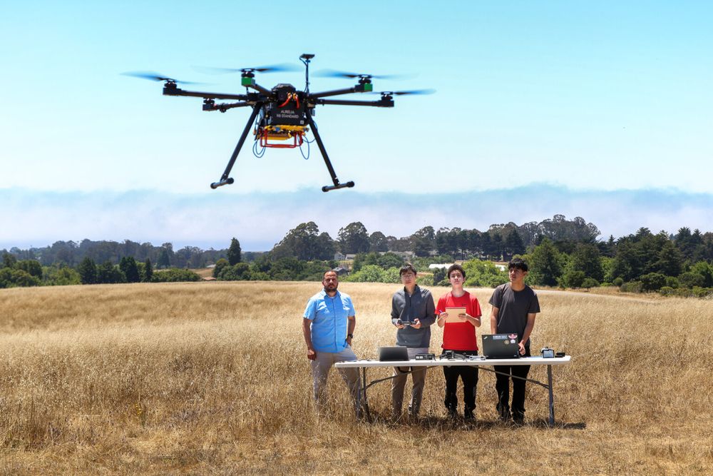four people gather in a field and fly a drone