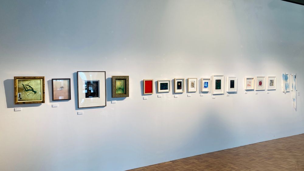 東北芸術工科大学、ロビーの展示。白壁に額装された小品たちが並ぶ。