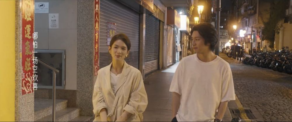 two people, mai you ge and xu jun le, walking down a nighttime street in macau