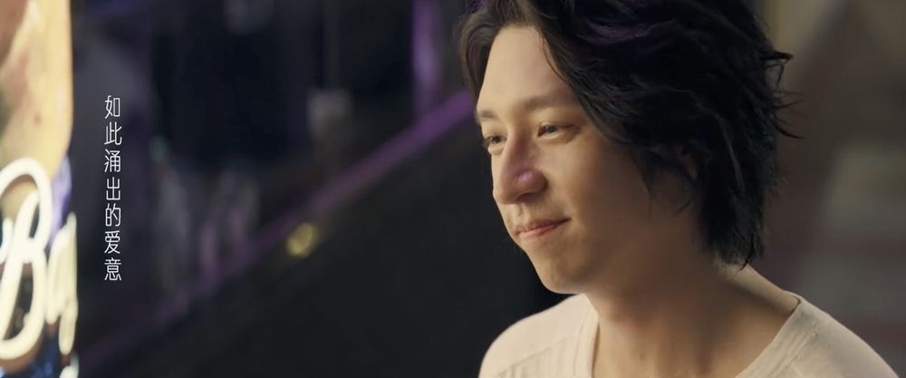 shoulders up closeup shot of xu jun le staring down affectionately at mai you ge (not in frame)