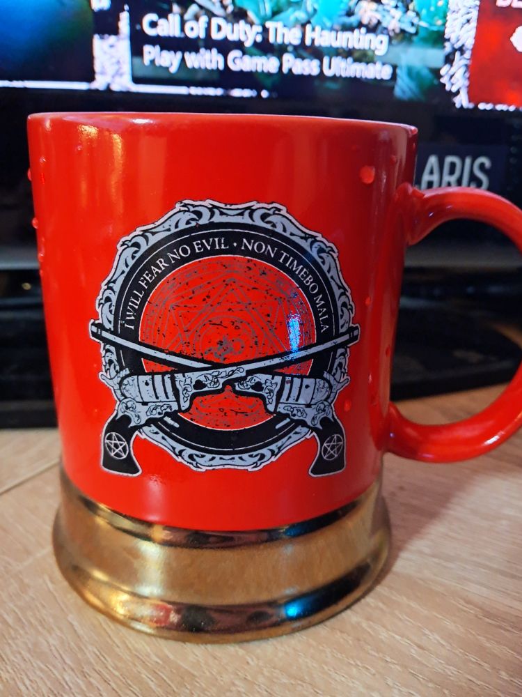 Mug shaped like a shotgun shell. There's an intricate design behind two revolvers. Each gun has a pentagram on it. The text reads i will fear no evil non timebo mala. 