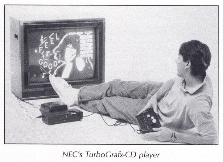 a young man lounging on the ground, propping himself up on his elbow, controller in hand, using the turbografx-cd player. an interface/menu is on the screen, showing a happy woman, some musical notes and the words 'feel good'.