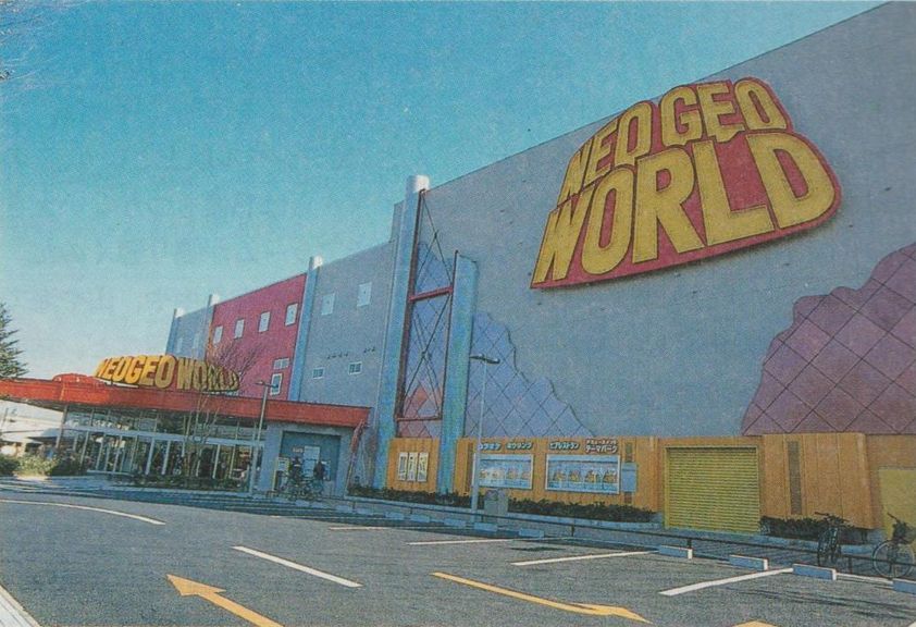 outside of the large neo geo world building with a large sign on the wall and smaller one where the entrance is.