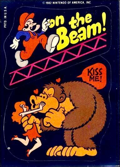 there are two stickers:
the top sticker is mario in his red overalls and hat, running across a metal beam. the bottom sticker is donkey kong trying to kiss a woman in a red dress and shoes with red or orange hair. there are love hearts in their air and his speech bubble says 'kiss me!'